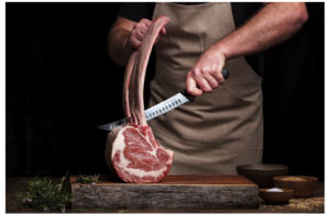 Man Cutting Tomahawk Steaks with knife